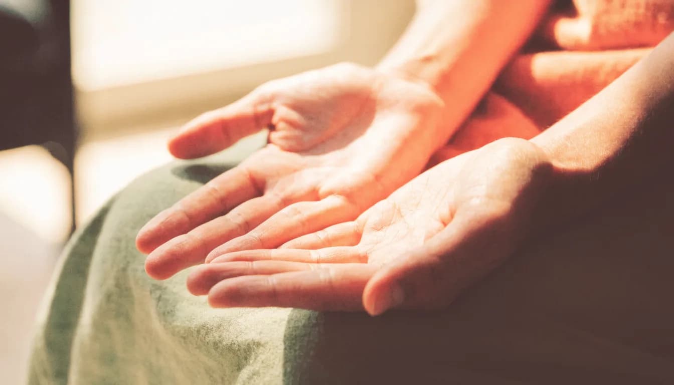 Open hands resting gently on a person's lap in a quiet, sunlit room, conveying a sense of being grounded and at peace.