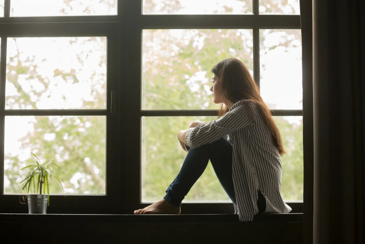 A woman sitting quietly by a window in soft daylight