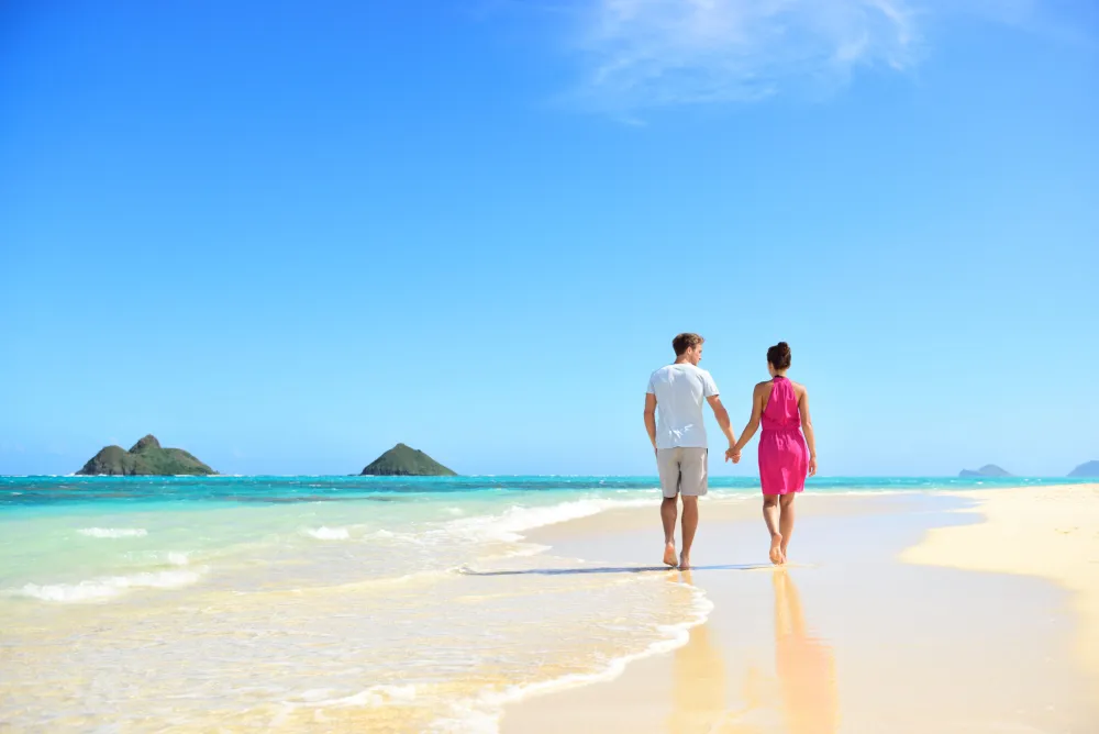 A couple walking hand in hand along a sunny beach