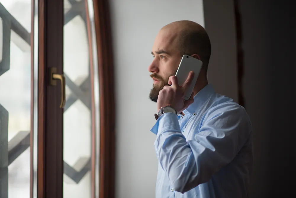 A man by a window talking on the phone
