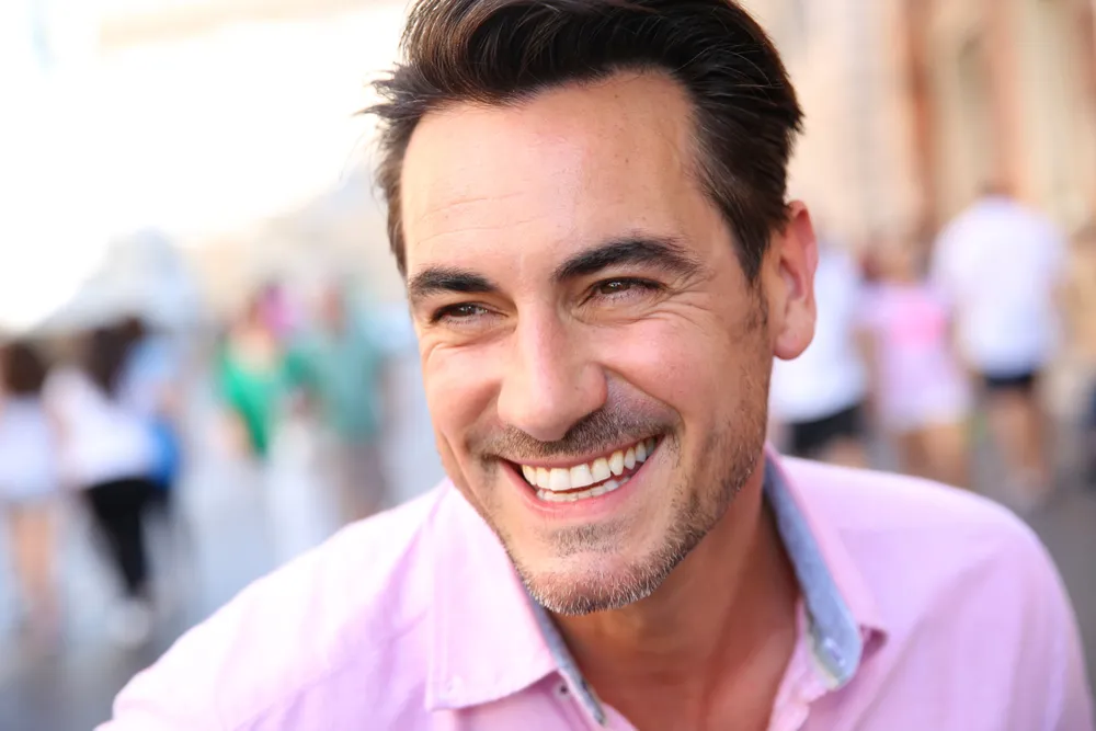 A man smiling warmly on a busy street