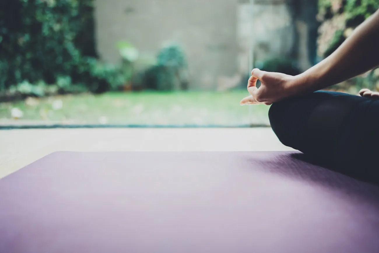 A person sitting cross-legged on a yoga mat in a calm, meditative pose