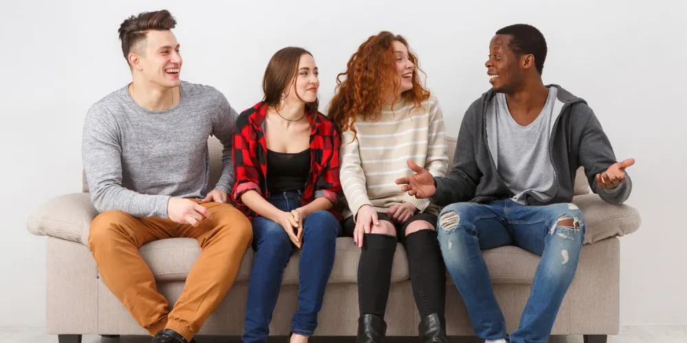 A small group of people sitting together on a couch, talking openly
