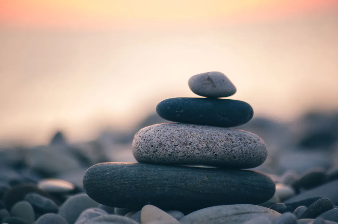 Smooth stones balanced in a stack against a soft sunset sky