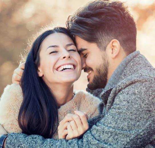 A couple embracing and laughing together outdoors