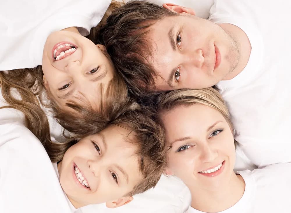 A smiling family of four lying with their heads together