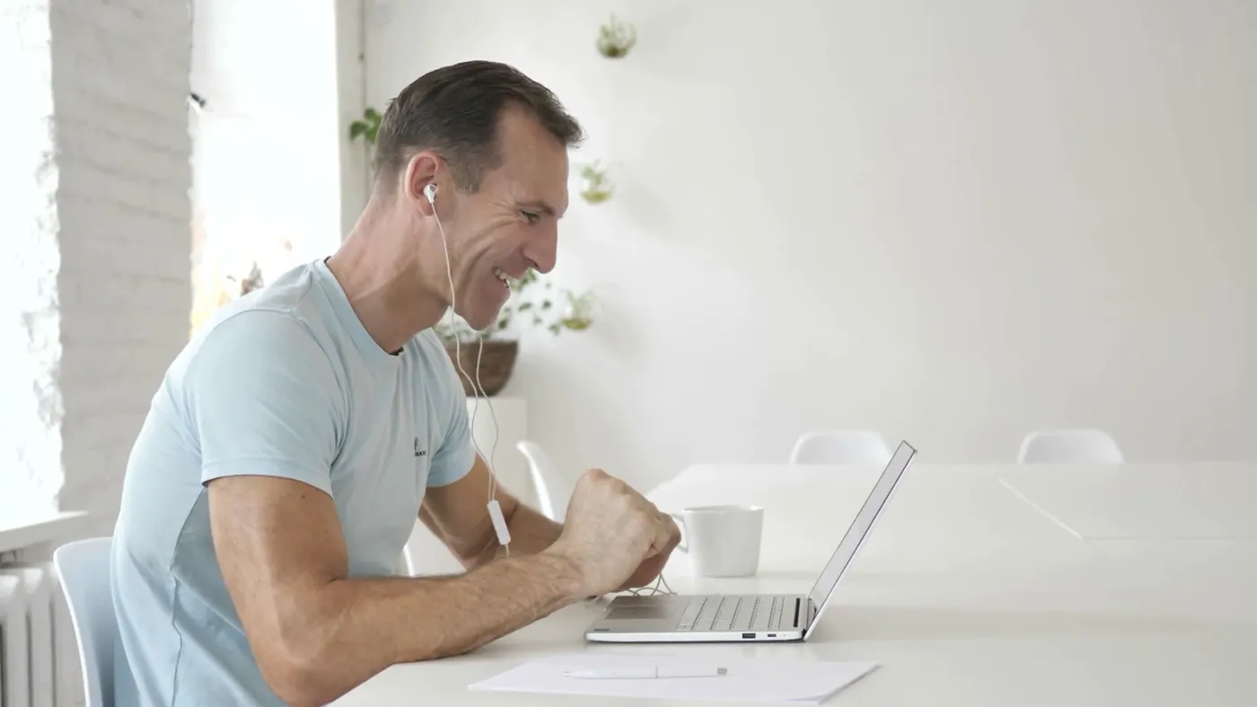 A man smiling during a video therapy session on his laptop at home