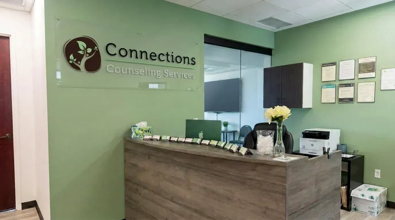 The welcoming Connections Counseling reception area with the practice logo above a wood-front desk