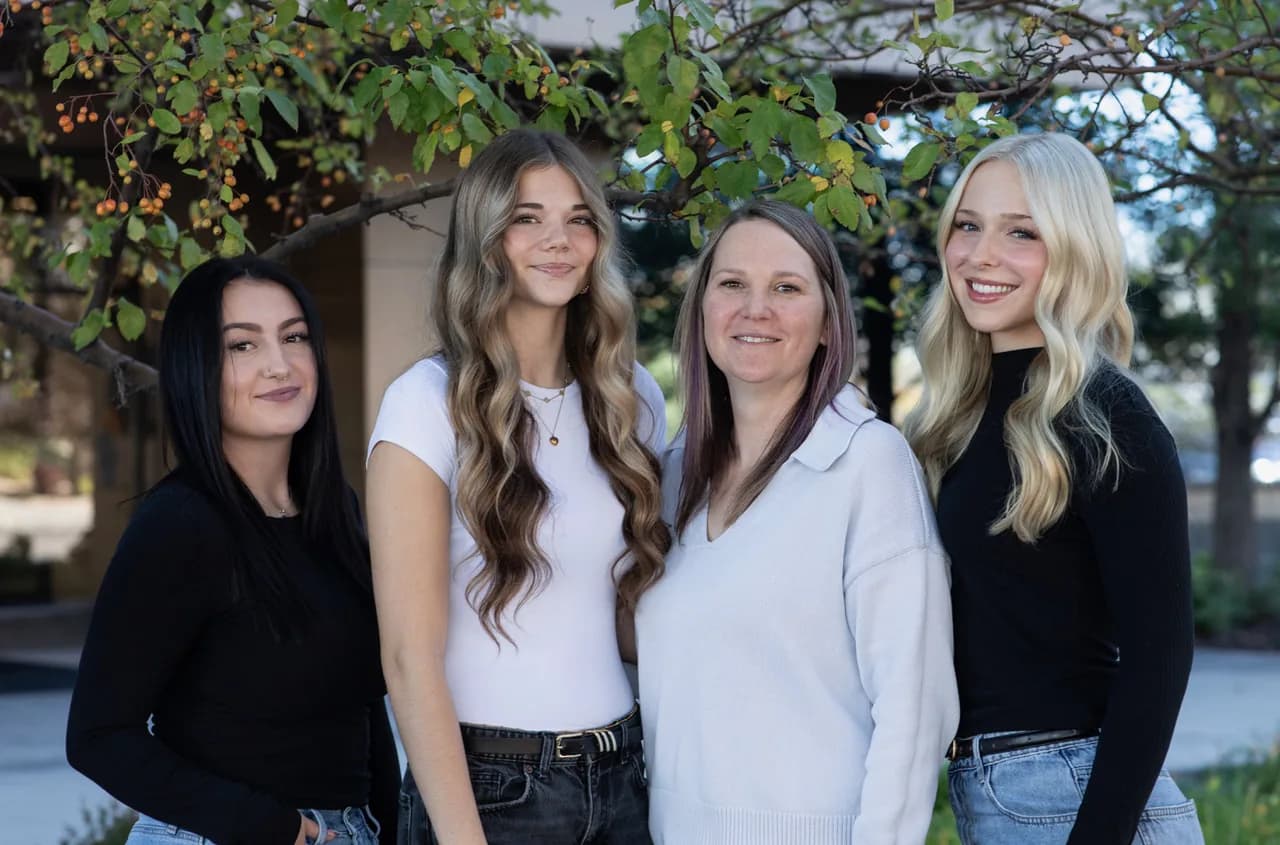Four members of the Connections Counseling administrative team smiling together outdoors beneath a leafy tree